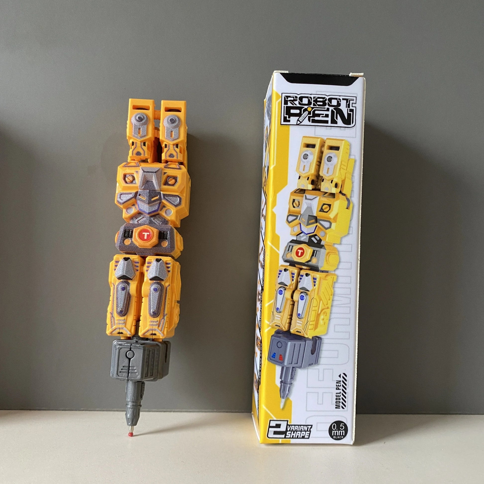 Stylo robot jaune type Transformer debout, boîte assortie en arrière-plan, design mécanique – Transformers.