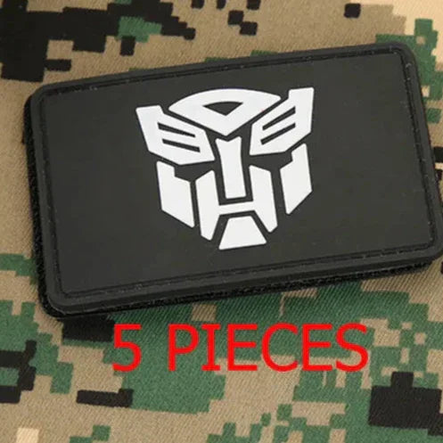 Patch noir logo Autobot blanc posé sur tissu camouflage, texte rouge 5 pieces – Transformers.