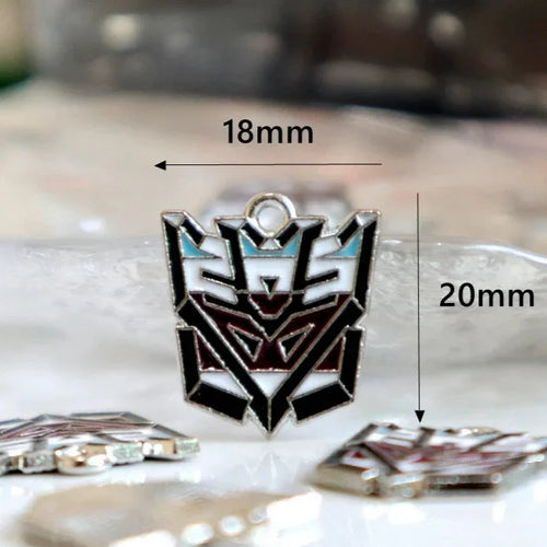 Pendentif émail tête Decepticon noir, blanc et bleu, 18mm x 20mm, posé sur surface claire – Transformers.