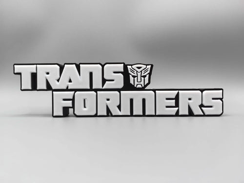 Transformers Plakette mit monochromem silbernem Logo – Metallisierte Schreibtischdekoration